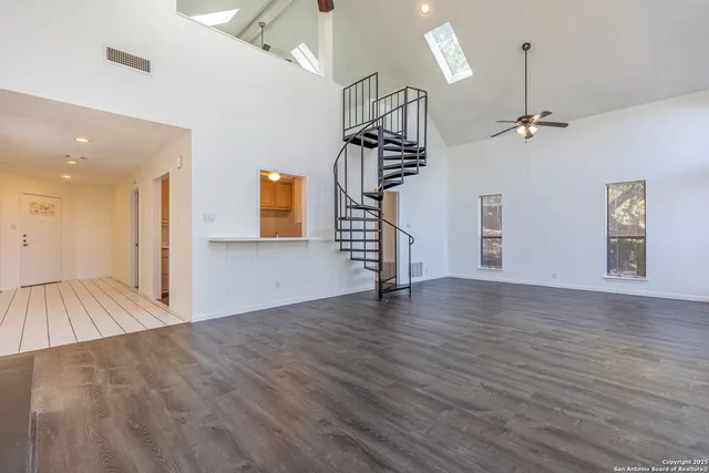 a view of empty room with wooden floor and ceiling fan