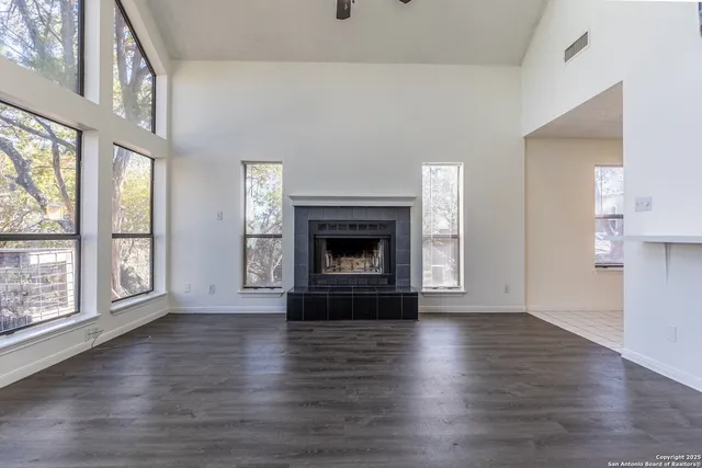 an empty room with wooden floor fireplace and windows