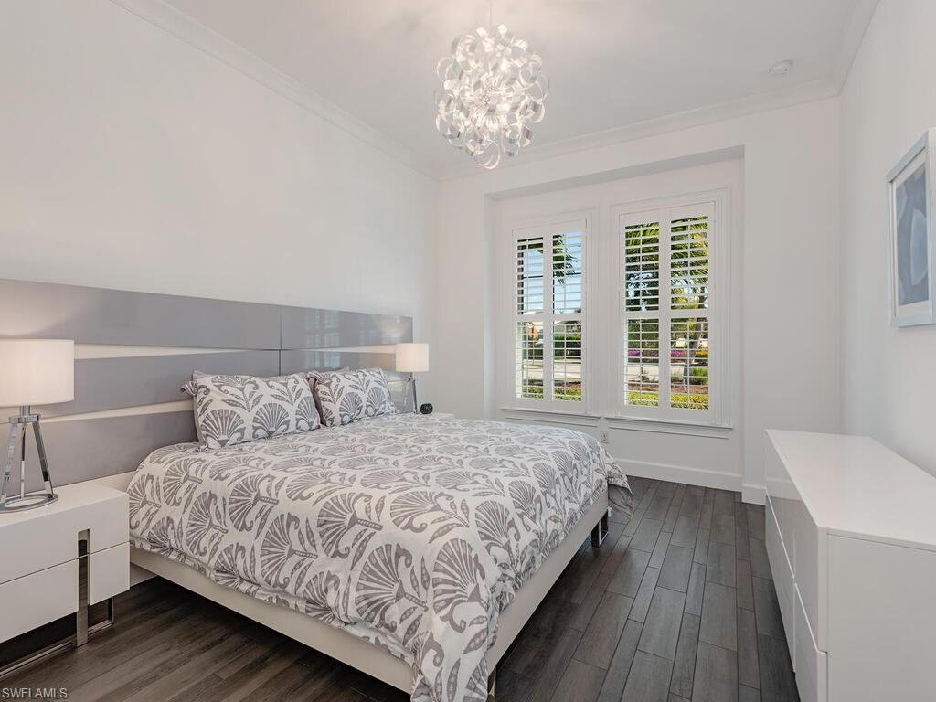6399 Warwick Avenue Naples, FL 34113 - Photo 11 of 30 a bedroom with a large bed chandelier and a window