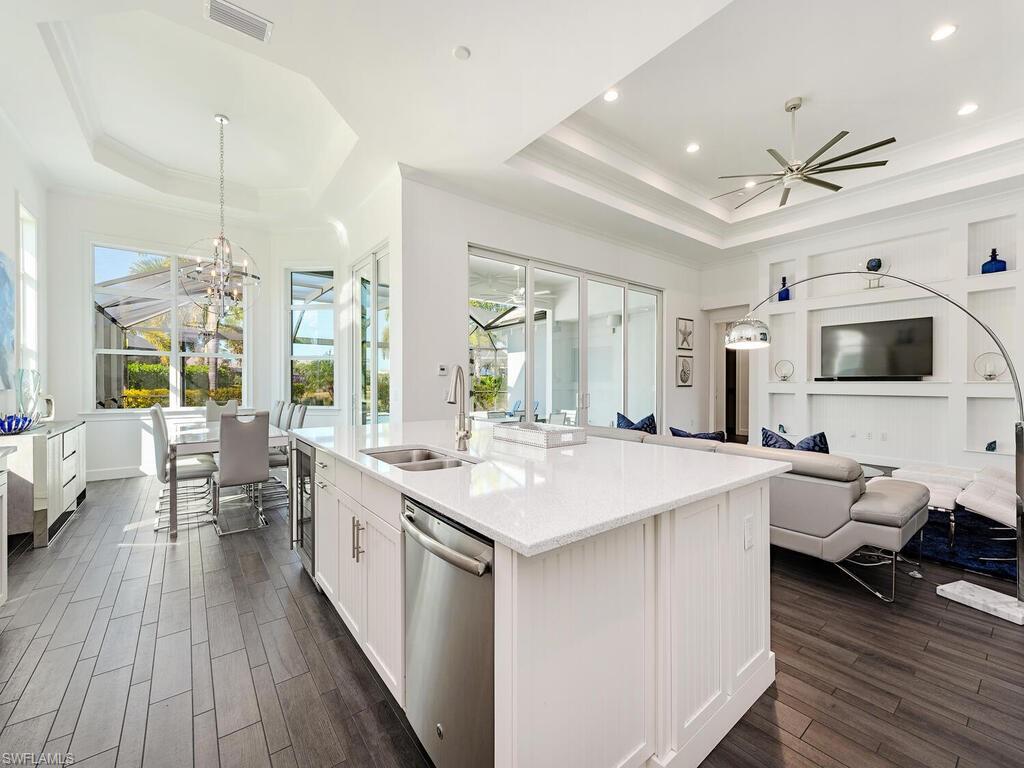 6399 Warwick Avenue Naples, FL 34113 - Photo 7 of 30 a large kitchen with stainless steel appliances a stove top oven a sink dishwasher and a dining table with wooden floor