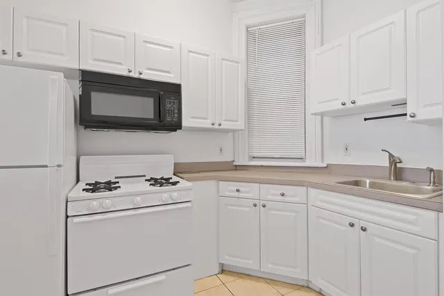 a kitchen with granite countertop white cabinets white stainless steel appliances and sink
