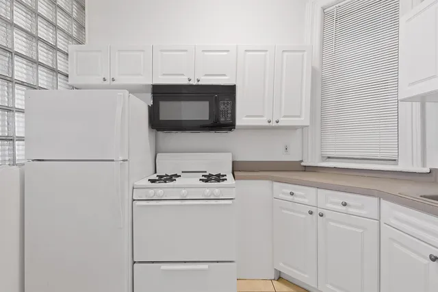 a kitchen with stainless steel appliances white cabinets and a refrigerator