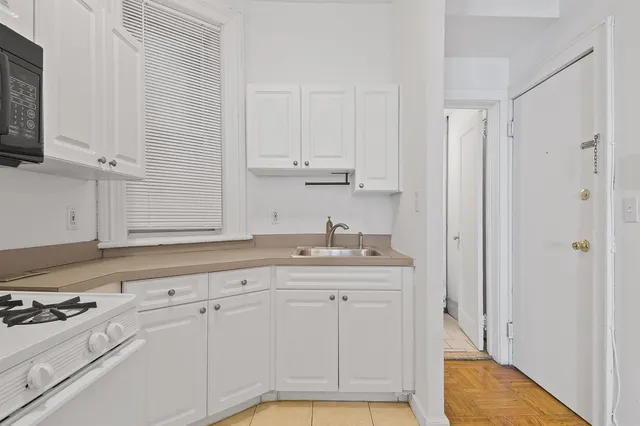 a kitchen with white cabinets and sink