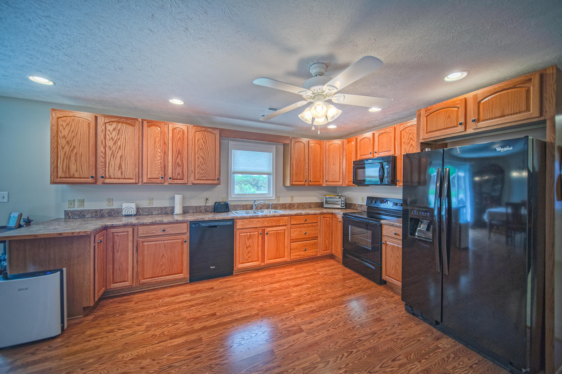3746 Horseshoe Bend Road Goodview, VA 24095 - Photo 12 of 35 a large kitchen with stainless steel appliances granite countertop a refrigerator a sink dishwasher a stove and white countertops with wooden floor
