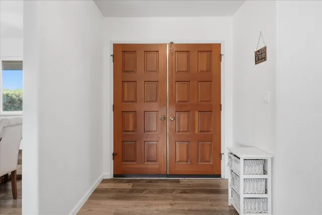 an empty room with wooden floor closet and windows