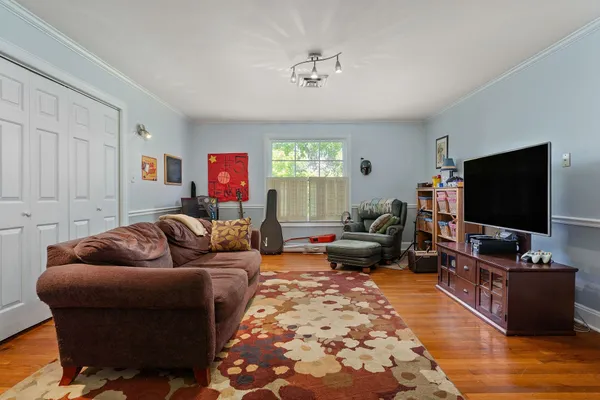 a living room with a baby crib furniture and a wooden floor