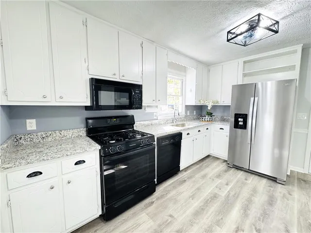 a kitchen with stainless steel appliances granite countertop a stove a sink and a refrigerator