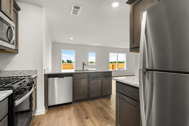 a kitchen with granite countertop a refrigerator stove and sink