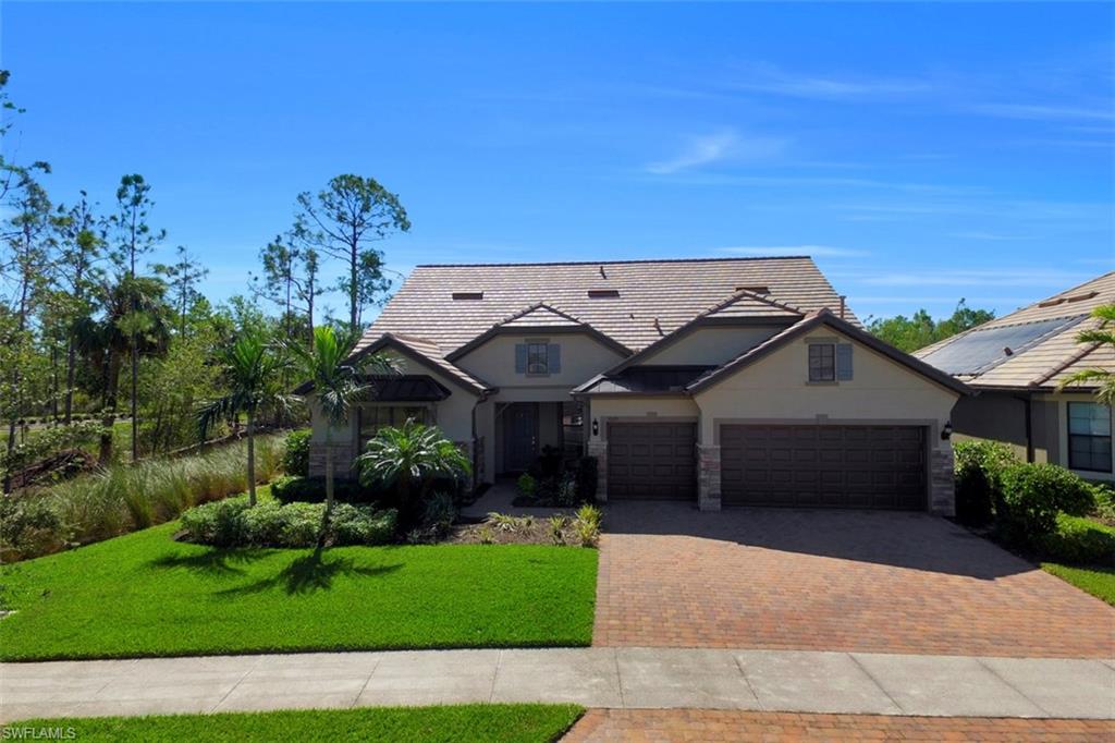 a view of a house with a yard plants and a large tree