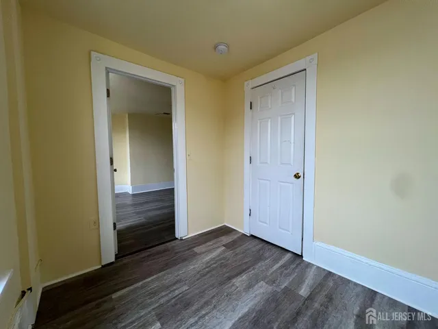 a view of an empty room with wooden floor and closet