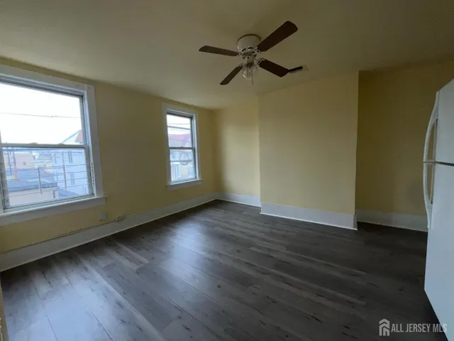a view of empty room with wooden floor and fan