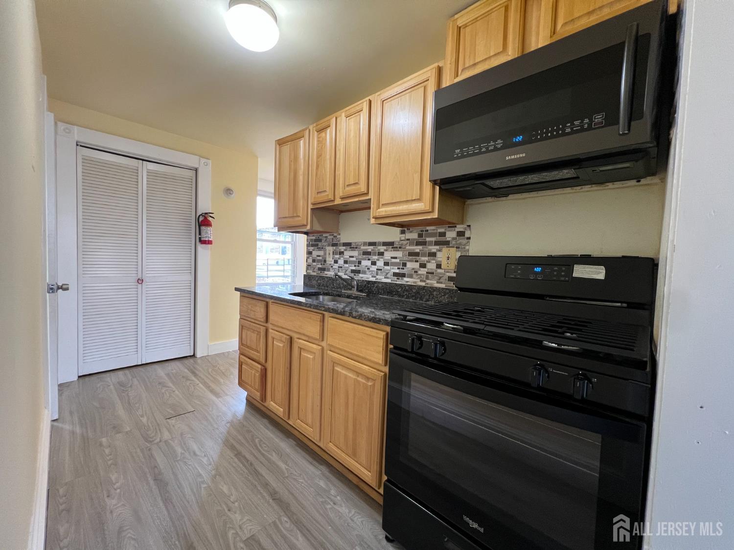 109 Washington Street, Unit 2 Perth Amboy, NJ 08861 - Photo 6 of 15 a kitchen with stainless steel appliances granite countertop wooden cabinets and a stove top oven