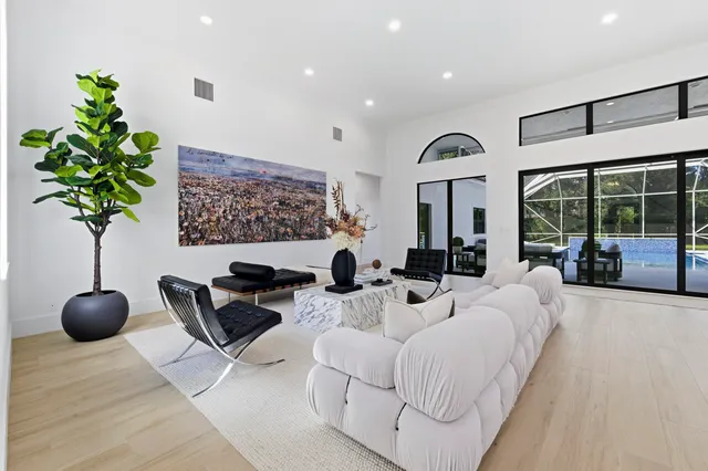 a living room with couches a coffee table and kitchen view with wooden floor