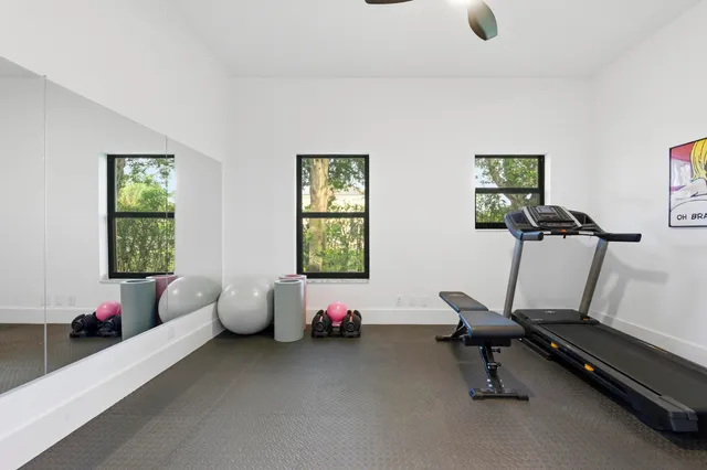 a white house with a big yard plants and large trees