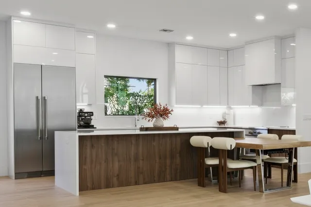 a kitchen with stainless steel appliances a dining table chairs and wooden floor