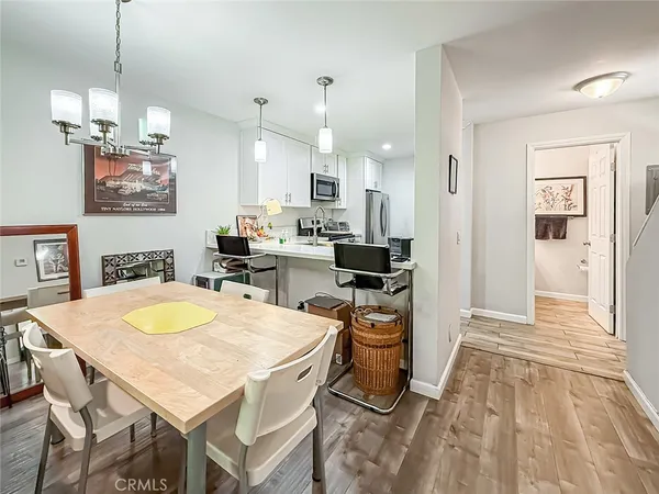 a open dining room with stainless steel appliances kitchen island granite countertop a table chairs and a refrigerator