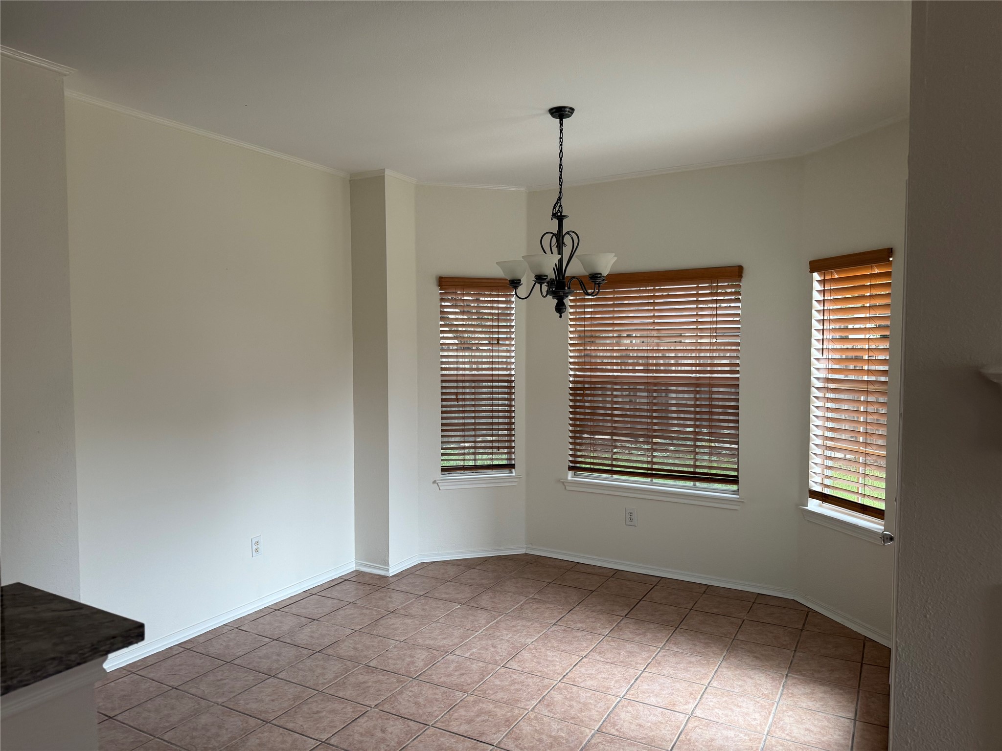 16910 Isle Of Man Road Pflugerville, TX 78660 - Photo 12 of 13 Bay window dining space featuring warm-toned floor tiles and a central chandelier