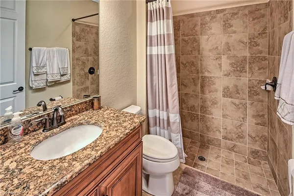 a bathroom with a granite countertop sink toilet a mirror and shower