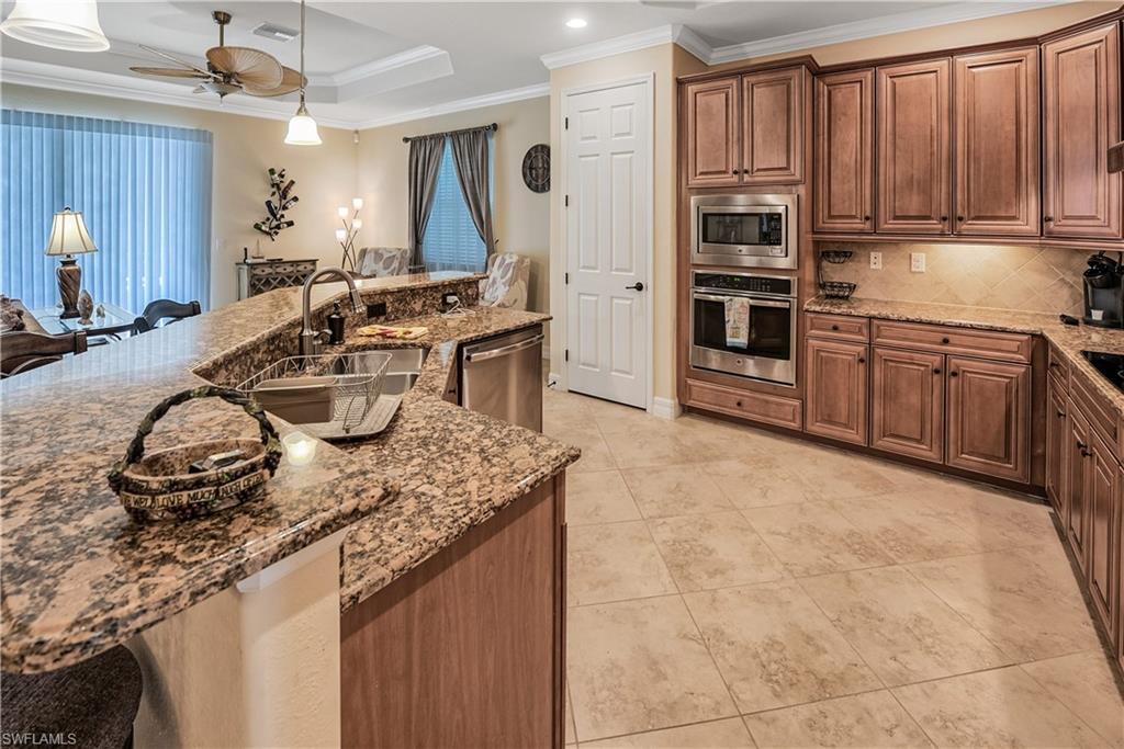9215 Veneto Lane Naples, FL 34113 - Photo 5 of 34 a kitchen with sink a stove and chairs