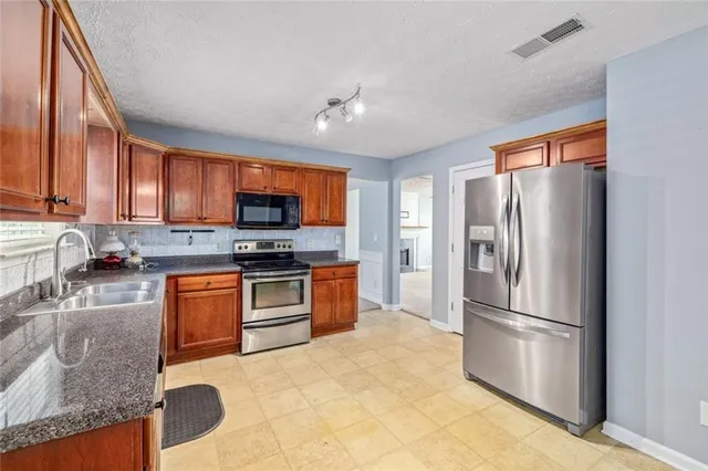 a kitchen with stainless steel appliances granite countertop a refrigerator stove microwave and sink