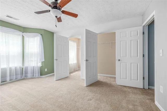 an empty room with windows and fan