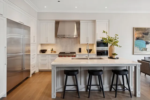 a kitchen with stainless steel appliances granite countertop white cabinets and wooden floor