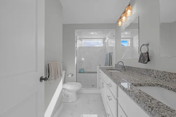 a spacious bathroom with a granite countertop sink a toilet and shower