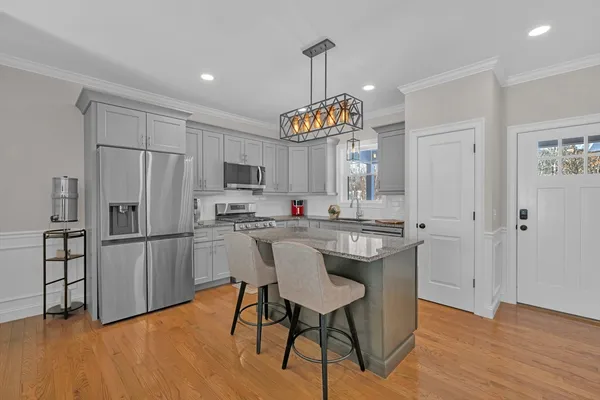 a kitchen with stainless steel appliances granite countertop a refrigerator a stove a sink dishwasher a dining table and chairs with wooden floor