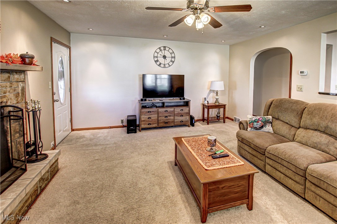 4234 Grafton Road Brunswick, OH 44212 - Photo 11 of 40 Carpeted living room featuring a stone fireplace, a textured ceiling, and ceiling fan