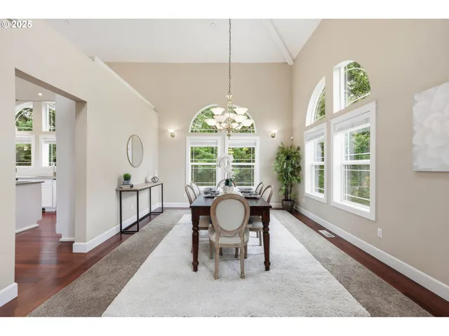 a dining room with wooden floor a chandelier a wooden table and chairs