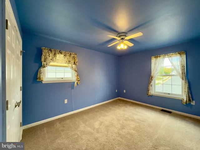 an empty room with windows and chandelier fan