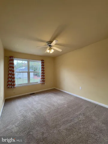 an empty room with a ceiling fan and window