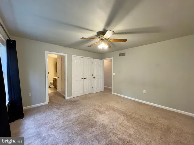 an empty room with closet and a ceiling fan