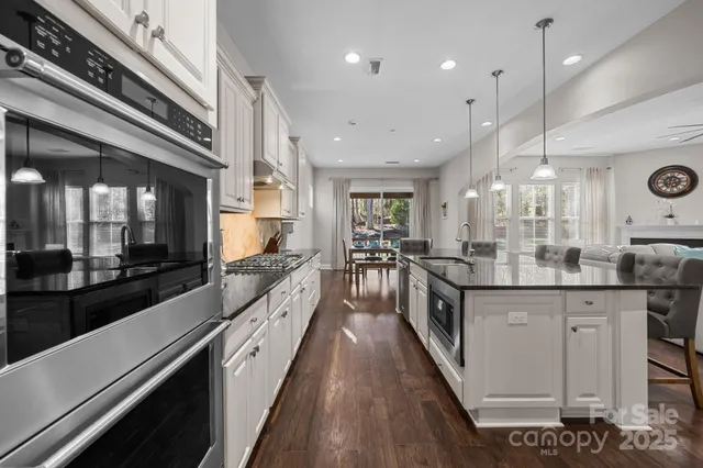 a kitchen with stainless steel appliances granite countertop a kitchen island a stove a refrigerator a kitchen island a dining table and chairs