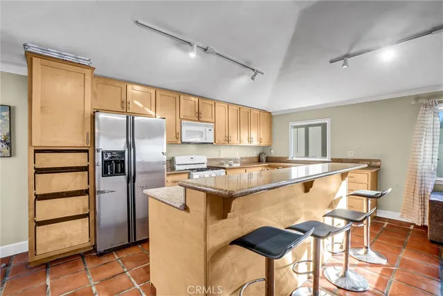 a kitchen with stainless steel appliances granite countertop a refrigerator a stove a sink and a dining table with chairs