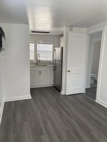an empty room with wooden floor cabinet and windows