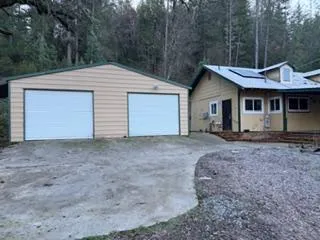 a view of a house with a yard and large tree