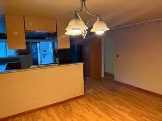 a view of a kitchen with a stove wooden floor and a hallway