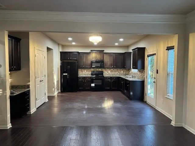 a large kitchen with a center island wooden floor stainless steel appliances and a window