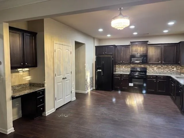 a kitchen with stainless steel appliances kitchen island granite countertop wooden cabinets a refrigerator a stove a sink and dishwasher with wooden floor