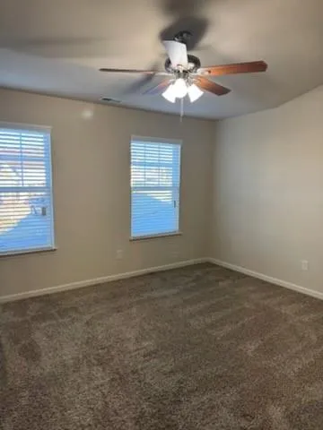 en empty room with windows and chandelier fan