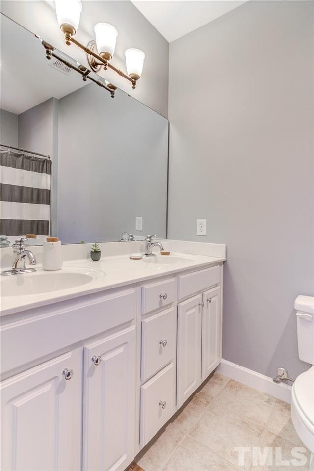 816 Cotton Exchange Court Raleigh, NC 27608 - Photo 13 of 25 a bathroom with a double vanity sink a toilet and a mirror