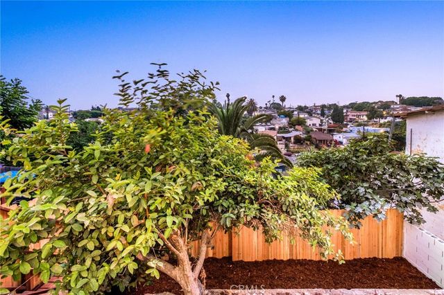 a view of a yard with plants and wooden fence