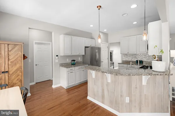a kitchen with stainless steel appliances granite countertop a refrigerator a sink and white cabinets