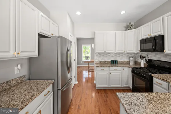 a kitchen with granite countertop a refrigerator stove top oven and sink