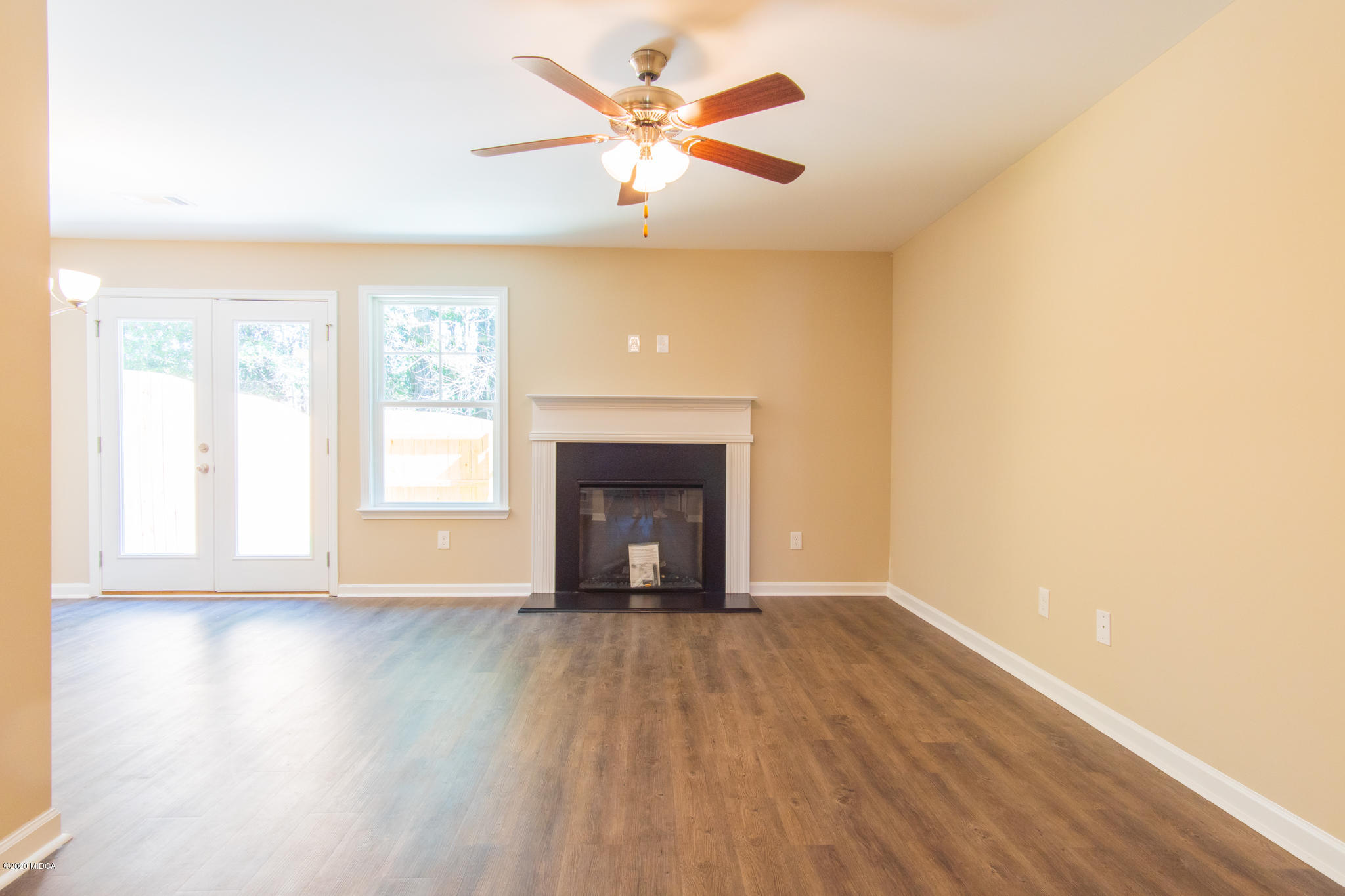 303 Pond View Road Macon, GA 31206 - Photo 3 of 33 an empty room with wooden floor a ceiling fan and windows