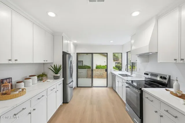 a kitchen with a sink dishwasher stove and white cabinets with wooden floor