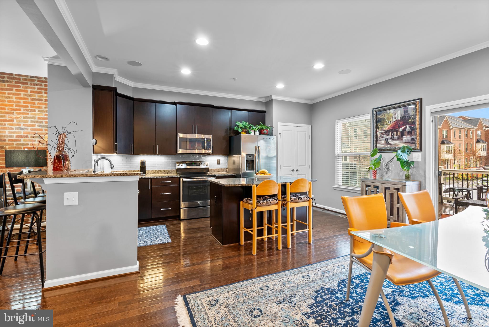 834 Oldham Street Baltimore, MD 21224 - Photo 11 of 55 a kitchen with stainless steel appliances kitchen island granite countertop a stove a sink a dining table and chairs with wooden floor