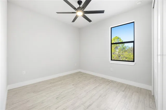 an empty room with a window and a ceiling fan