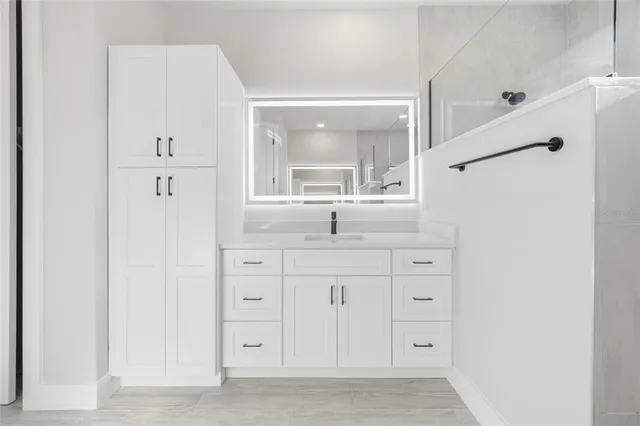 a bathroom with a granite countertop sink mirror and cabinets